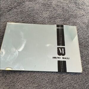 Bruno Magli signature logo double-sided mirror. 3 3/4 x 2 1/2 inches.